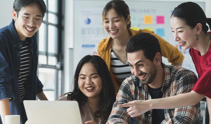A group of happy EB5 investors who qualify for reserved set-asides pointing at a computer screen.
