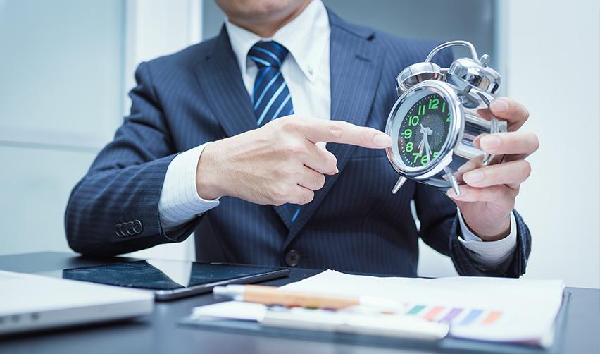 An immigration attorney with EB5 supporting documents on his desk pointing at a clock, symbolizing EB5 visa backlogs.