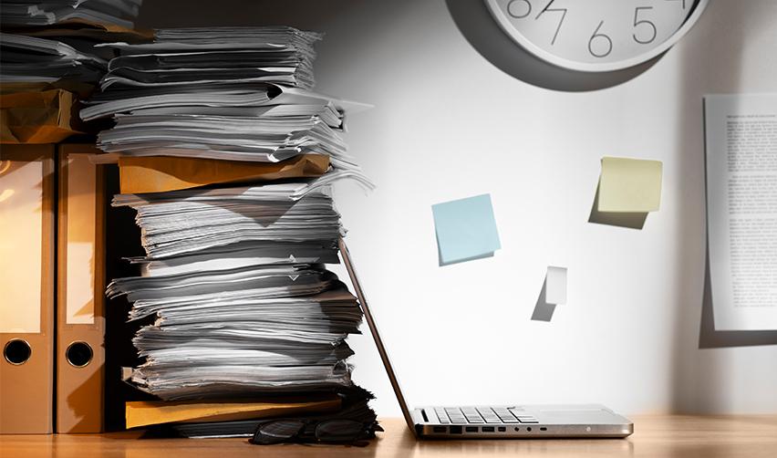 Some EB5 visa files and supporting documents piled up behind a computer, symbolizing visa backlogs and retrogression.