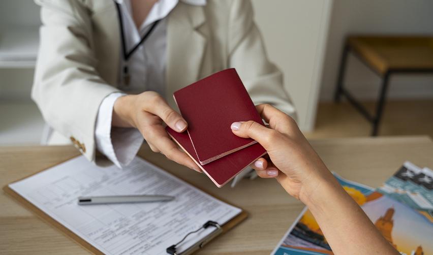 A foreign investor handing two passports to an immigration officer for form processing.