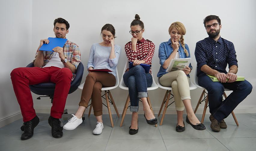 Green Card applicants sitting on chairs in a waiting room.