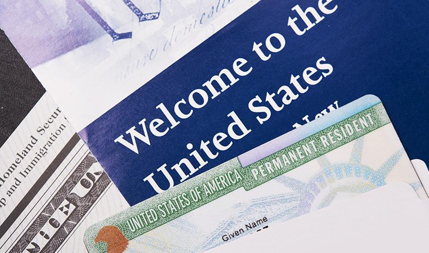 A permanent resident card or green card on the USCIS documents reading welcome to the United States.