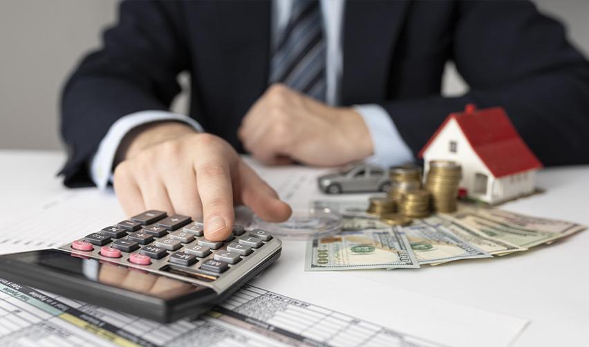 A tax attorney or IRS officer doing some calculations with money and a model house on his desk, symbolizing the financial benefits of holding an EB5 green card.