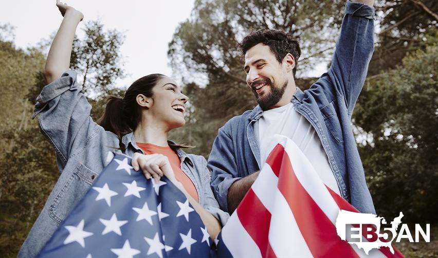 Happy foreign investors celebrating their EB5 green card with the U.S. flag in their hands, with the EB5AN logo on the corner.