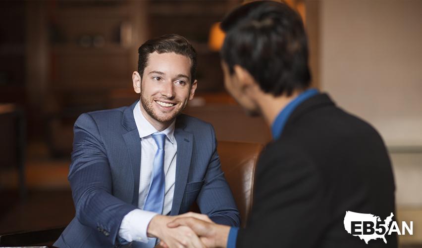 An EB5 green card holder shaking hands with a regional center managing partner, with the EB5AN logo on the corner.
