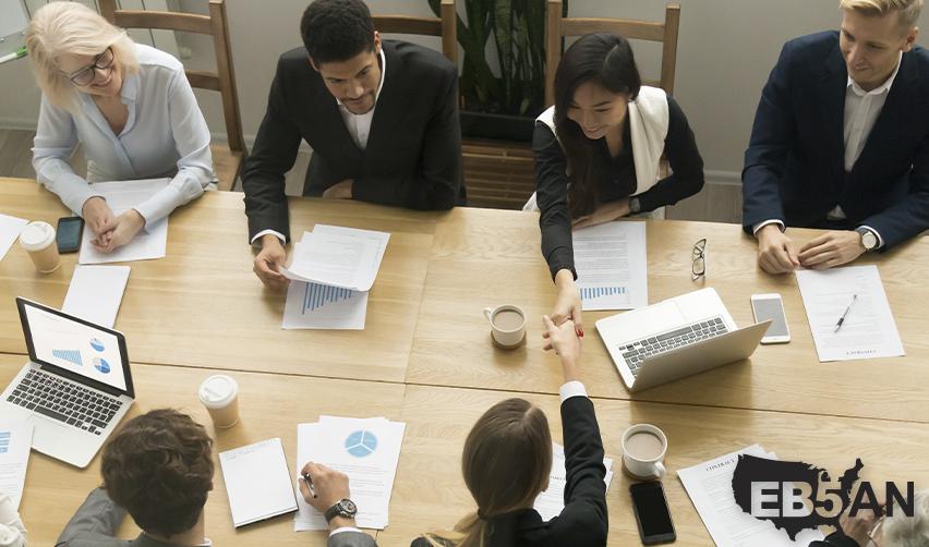 A regional center team of EB5 industry professionals having a meeting with foreign investors at an office with the EB5AN logo on the corner.
