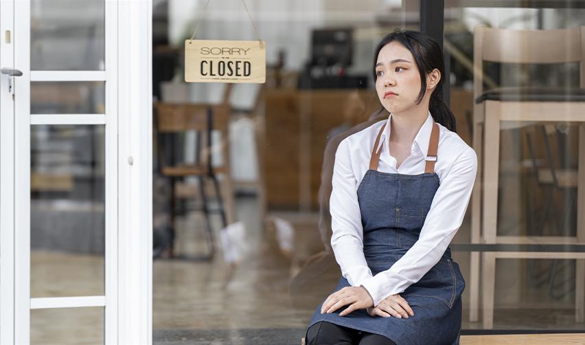 Distressed small business owner sitting outside a closed shop, symbolizing the challenges of direct EB5 investments.