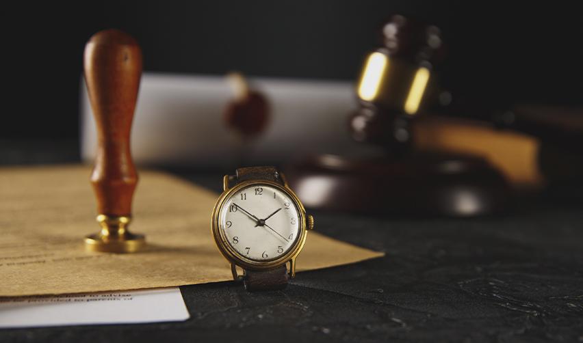 A close-up of a watch on a judge or attorney's desk with legal documents and objects on it, symbolizing filing a mandamus for EB5 processing delays.