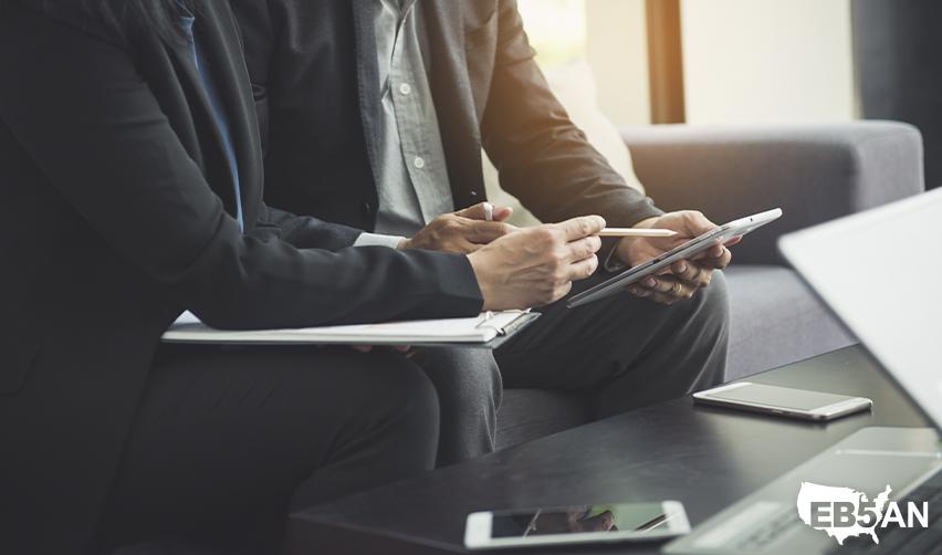 Two professionals reviewing EB5 investment paperwork, highlighting the importance of expert guidance for the EB5 visa process, with the EB5AN logo on the corner.