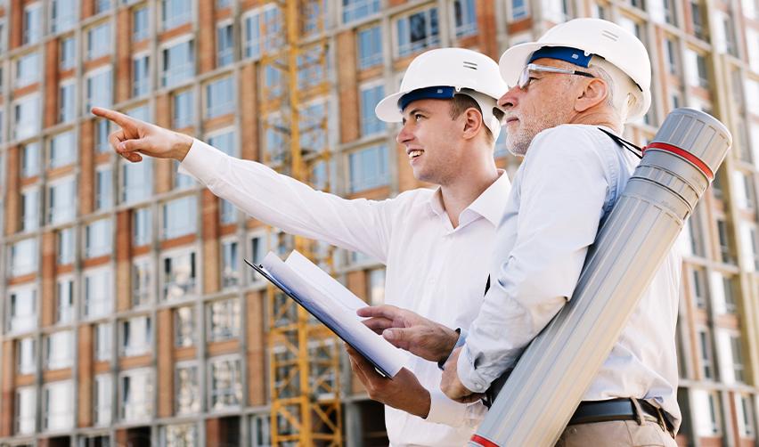 Two EB5 regional center team members in hard hats pointing at a construction site, symbolizing EB5AN's expertise in offering low-risk EB5 projects to help investors achieve financial and immigration success.