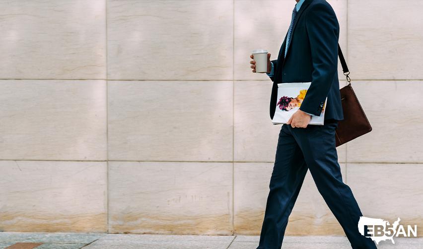 A business owner or CEO walking on the street, with the EB5AN logo on the corner, symbolizing the career opportunities that an EB5 green card offers.