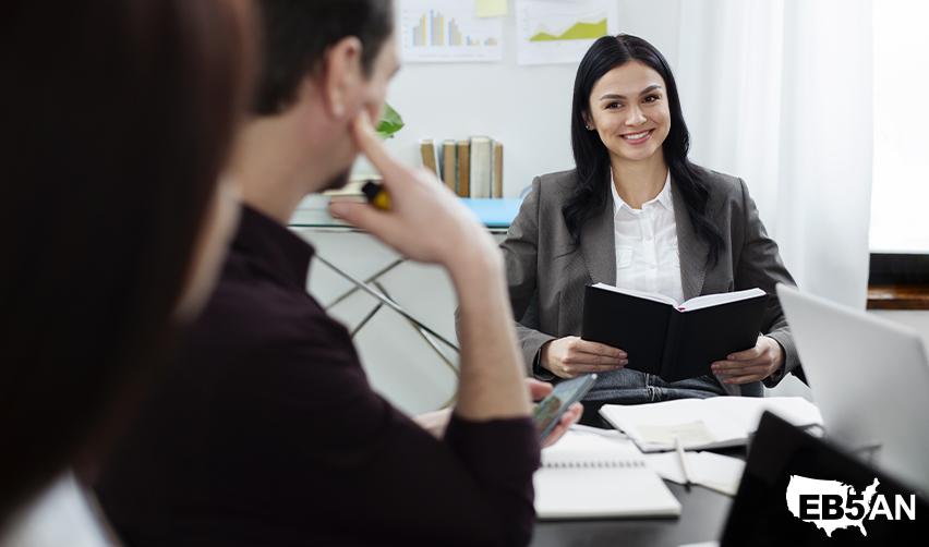 An EB5 regional center employee having a meeting with EB5 investors at an office, with the EB5AN logo on the corner.