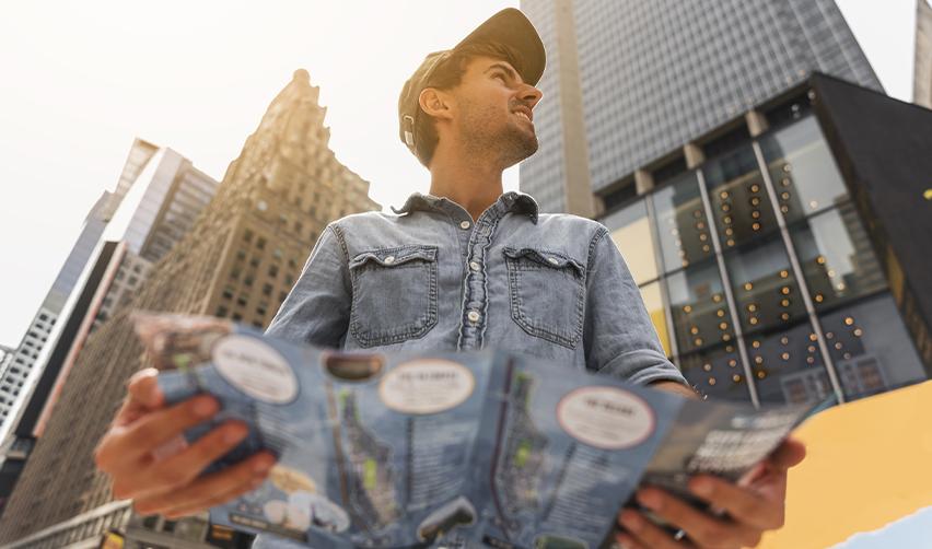An EB5 investor on an urban street with an investment catalog in his hand, considering EB5 urban TEA investment projects.