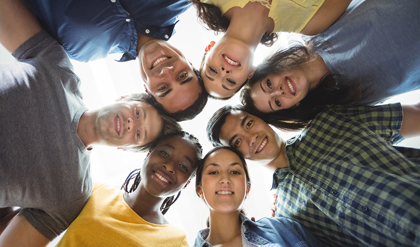 A diverse group of smiling international students looking down, highlighting the EB5 program's accessibility to individuals from all nationalities and backgrounds.