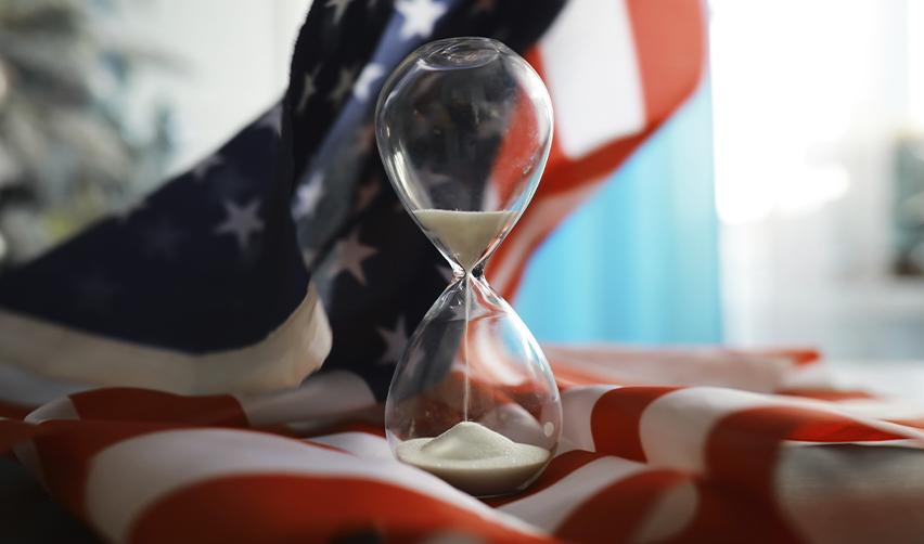 Hourglass placed on an American flag, representing the EB5 visa timeline for achieving US citizenship.