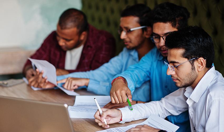 A group of skilled workers reviewing documents, highlighting the challenges of the H1B visa process compared to the straightforward EB5 Green Card pathway.