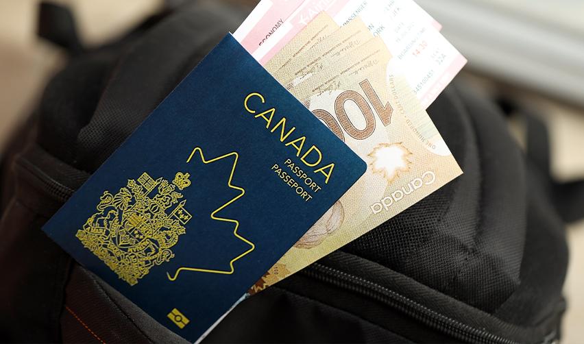 A close-up of a Canadian passport tucked into a backpack, with Canadian currency visible. Represents the financial readiness of Canadians pursuing U.S. green cards through EB5 investments.