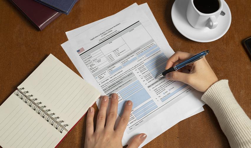 Filing adjustment of status with Form I485 alongside a notebook and coffee, illustrating the paperwork process for EB5 Green Card applicants.