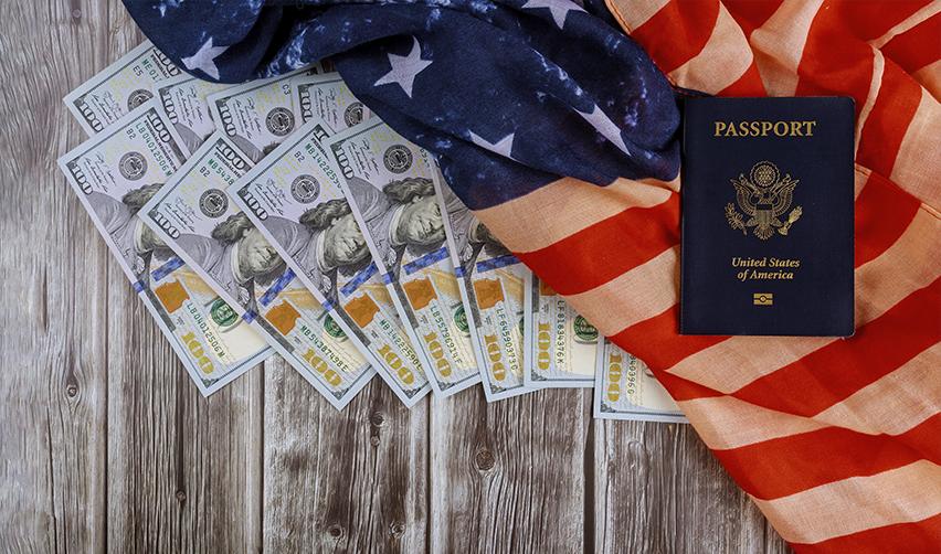 U.S. passport placed on an American flag with stacks of $100 bills, representing changing investment amounts in the EB5 program.