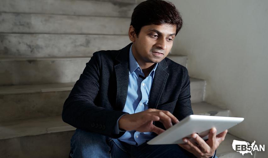 An Indian EB5 investor using a tablet, symbolizing the EB5 process and digital resources provided by EB5AN for immigrant investors.