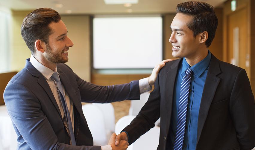 EB5 industry professionals shaking hands in a formal meeting, representing partnerships and success in EB5 investments with the help of EB5AN.