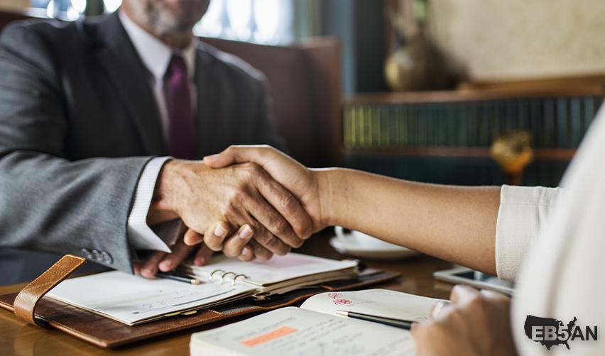 Close-up of a handshake between two professionals discussing EB5 investment documentation with the EB5AN logo on the corner.