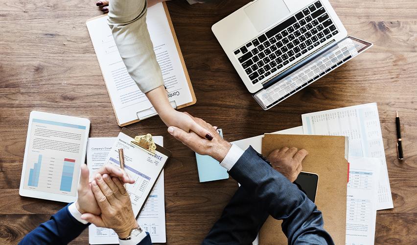 Business professionals shaking hands over investment documents, symbolizing EB5AN's partnership and collaboration in EB5 investment projects.