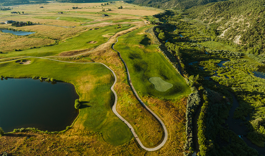 A golf course with a lake and mountains in the background