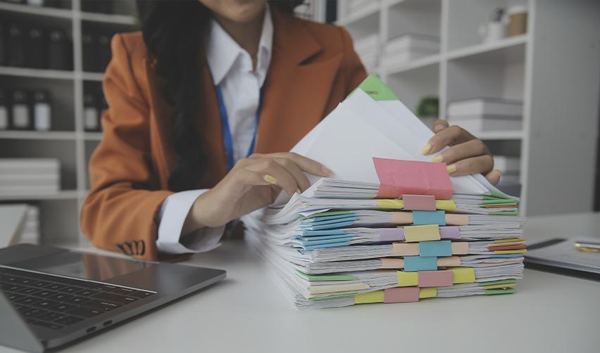 Business professional organizing a large stack of EB5 immigration documents, emphasizing the importance of accurate financial records and USCIS paperwork compliance.