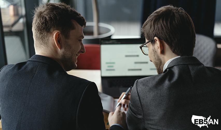 The EB5AN logo next to two regional center industry professionals discussing EB5 investment opportunities while reviewing charts on a laptop screen. Optimize your chance to secure a U.S. Green Card in 2025 through EB5.