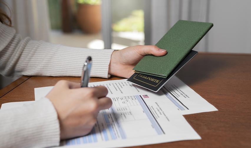 A person holding a passport while completing immigration forms, illustrating the adjustment of status process for EB5 visa applicants.