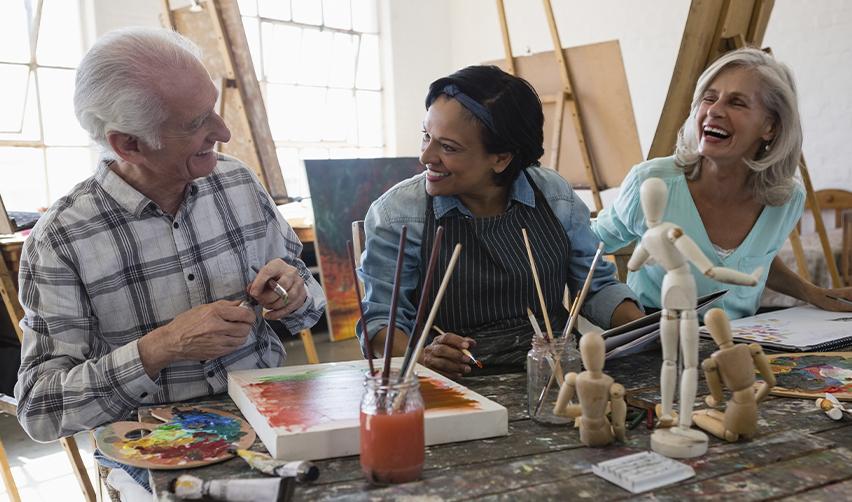 Three 55+ residents enjoying an art class at Club Cresswind's art studio in Twin Lakes, Georgia, highlighting the vibrant, social lifestyle of this active adult community.