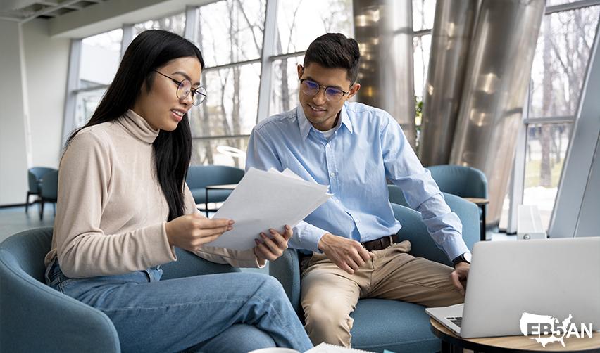 Two business professionals reviewing EB5 investment documents, illustrating how working with experienced regional centers like EB5AN can streamline the Green Card process.