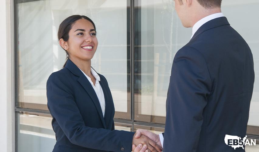 The EB5AN logo next to two people in a professional business meeting showcasing trust and partnership, highlighting the benefits of the EB5 visa program for 2025 tech layoff affected individuals.