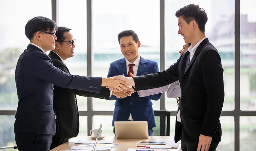 A group of business professionals shaking hands after a successful EB5 investment discussion. Establishing a direct relationship with regional center principals can provide confidence in investment decisions.