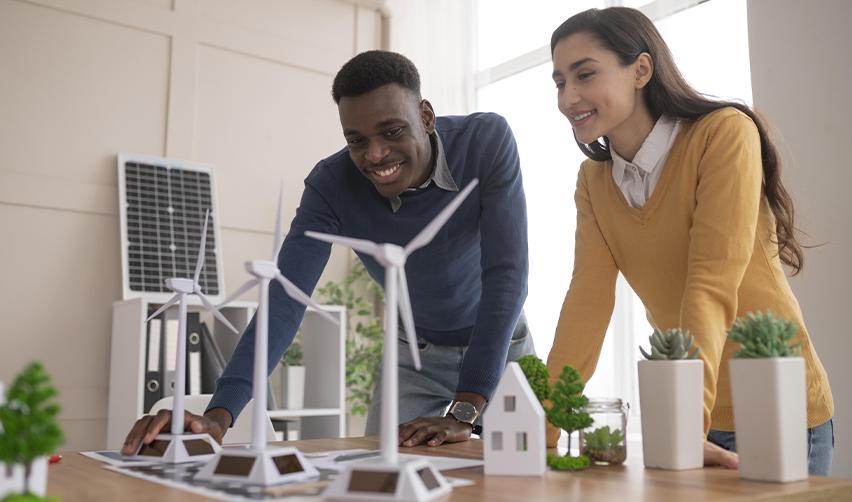 Two professionals reviewing a model of a sustainable housing project, representing eco-friendly real estate development and EB5 investment opportunities in energy-efficient single-family homes.