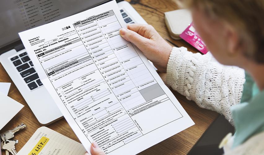 Close-up of an EB5 investor reviewing a 2024 Schedule K1 form. Key tax documents like K1 forms detail taxable income and deductions for U.S. tax filings.