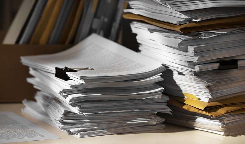 A large stack of legal documents and visa application papers, representing the EB5 visa backlogs in the unreserved category.