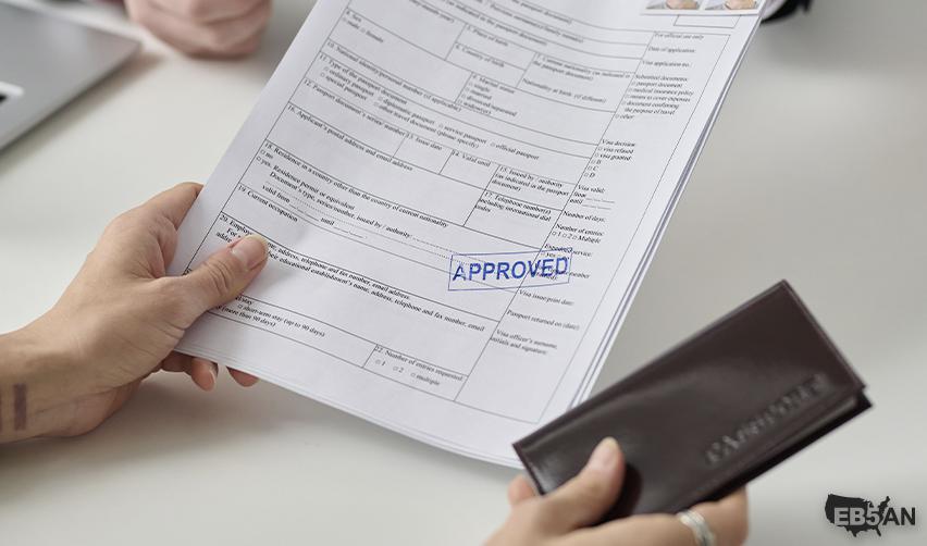 A close-up of hands holding an approved immigration document stamped