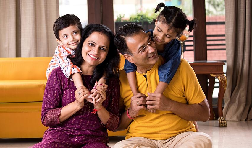 A smiling Indian family enjoys quality time together at home, reflecting the aspirations of Indian immigrants who seek stability with an Eb5 Green Card amid changing local law enforcement policies on visas and residency.