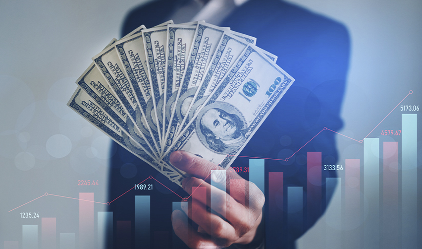 Hand holding dollar bills in front of financial graph. Visual representation of EB5 investment strategy using U.S. earnings and financial planning.