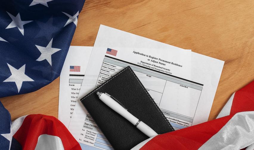 Close-up of U.S. immigration forms and American flag, illustrating the EB5 Green Card and citizenship application process.