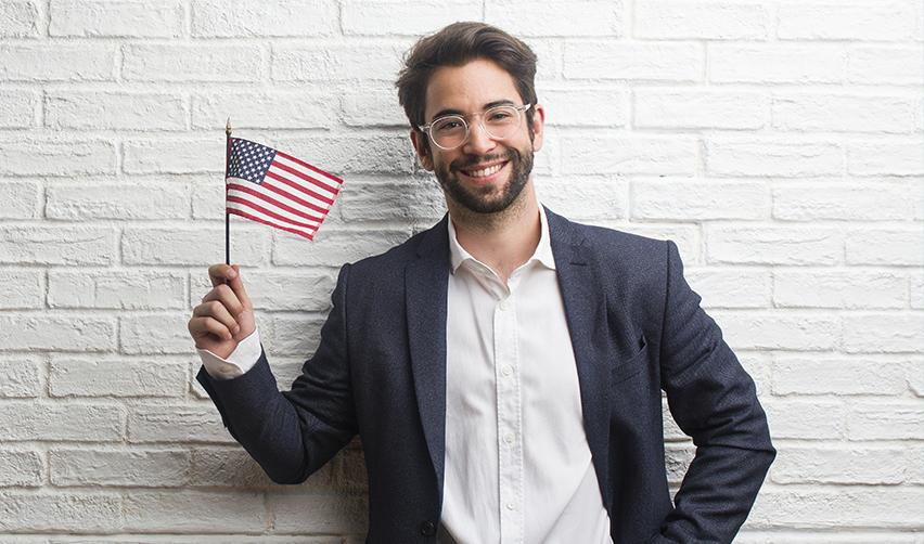 Happy immigrant holding a small American flag, representing successful transition to U.S. permanent residency through the EB5 program with the help of EB5AN.