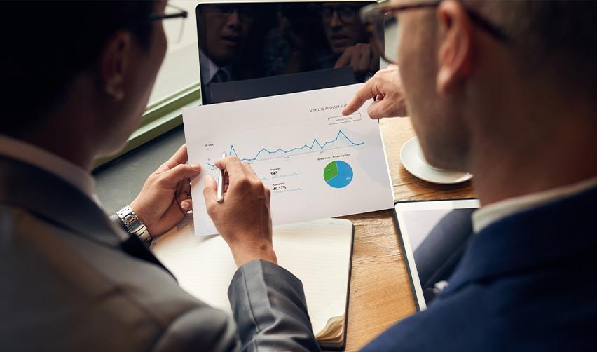 Two professionals analyzing market data and charts, illustrating the strategic planning and financial outlook behind EB5 real estate investments.