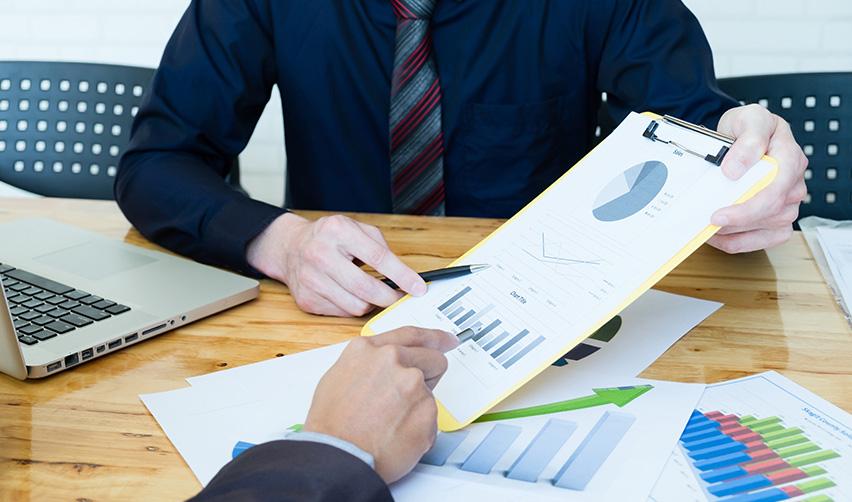 Business meeting with regional center professionals reviewing investment performance charts and financial reports—illustrating the due diligence process for EB5 investment evaluation.