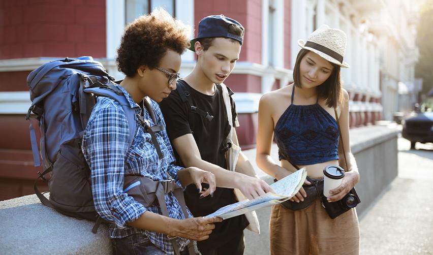 Young travelers checking a map during an international trip, representing EB5 visa applicants planning travel during the immigration process.