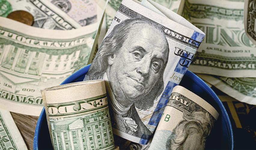 Close-up of rolled U.S. dollar bills, symbolizing capital investment required for EB5 and E2 visa programs.