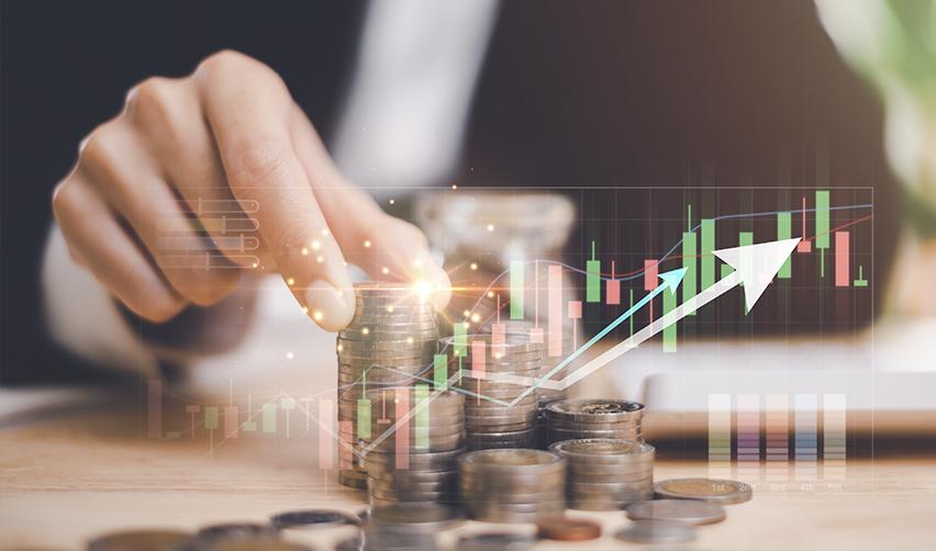 A hand stacking coins in front of a digital graph, representing financial growth and the capital investment process involved in the EB5 regional center program.