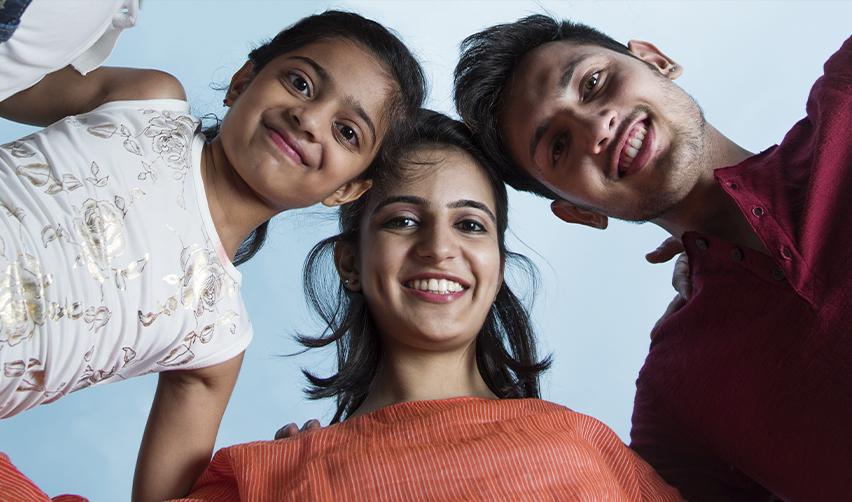 Happy Indian siblings smiling under blue sky, symbolizing EB5 families aiming to protect children from aging out of Green Card eligibility.