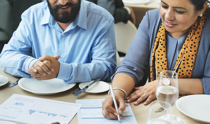 Indian couple reviewing EB5 investment documents, preparing for their Green Card application and future U.S. citizenship with EB5AN's help.
